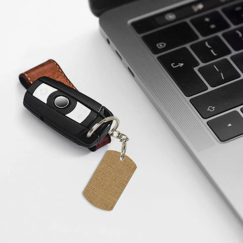 Rock Solid Large Grid Weave Jute Texture Rectangle Plated Metal Keychain next to a laptop key, showcasing daily carry versatility.