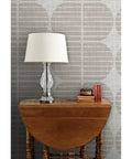 Super Sleek Geometric Stripe Vinyl Wallpaper Shows Off Subtle Leather Texture And Delivers Knockout Durability For Heavy Traffic Commercial Spots Or Wild Home Rebounds Featuring Type Ii Sturdiness And Custom Prints That Bring The Real Deal Vibes on a beige wall with a lamp and books.