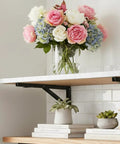 Heavy Duty Folding Shelf Brackets 12 Inch 2 Pack Wall Mounted Drop Down Table with flowers and books on shelf.