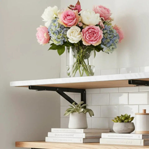Heavy Duty Folding Shelf Brackets 12 Inch 2 Pack Wall Mounted Drop Down Table with flowers and books on shelf.