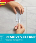 Bathroom Accessory Organizer With Two Medium Water Resistant Strips Satin Nickel Finish Holds Up To 2 Lb No Tools Needed Damage Free Stick On Wall Mount Keeps Counter Clutter Free being removed from wall with hands.