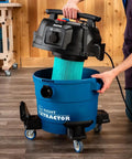 9 Gallon HEPA Dust Collector Auto Starts With Your Power Tools being used to insert a washable filter into blue heavy duty vacuum.