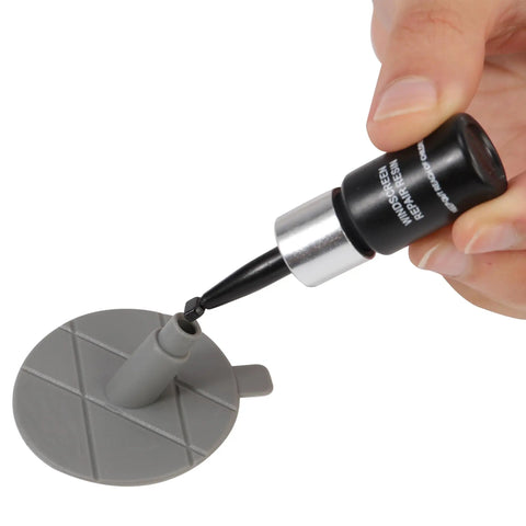 Close-up of Windshield Repair Kit For Chips And Cracks Quick Fix Auto Glass Repair Tool in use with gray resin applicator on pad.