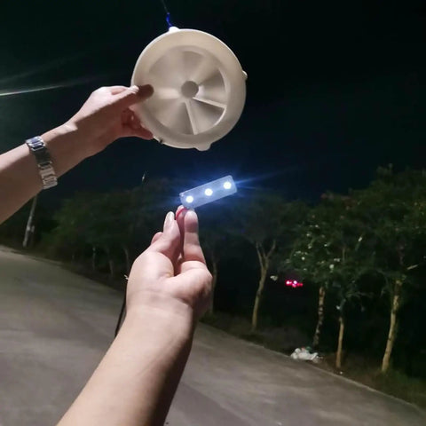 Person holding a Dual-Mode Portable Wind And Water Turbine Generator For Outdoor Power Small Hydroelectric Micro Turbine at night.
