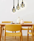 Industrial 3 Light Pendant With Adjustable Cords Vintage Farmhouse Black Metal Cage Light hanging over dining table