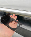 2 Pack Pin Trailer Wiring Connector Mounting Brackets For 7 Way RV Socket And Vehicle Trailer Plug, Heavy Duty Iron Mounts With Easy Install No Fuss, Rock Solid Power Transmission, Compatible For Secure Towing black iron bracket with hand, shown beside vehicle for 7-way RV socket