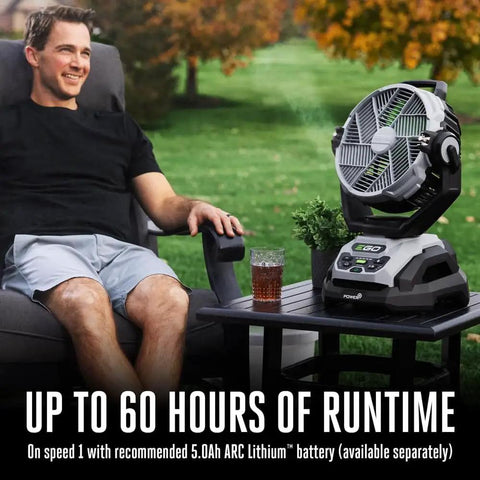 Man sitting outdoors with Beast 10 Inch Oscillating Misting Fan With 1700 CFM And 20 MPH Air on a table beside him