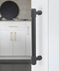 Installed 5-inch matte black knurled cabinet handle shown on white kitchen cabinet