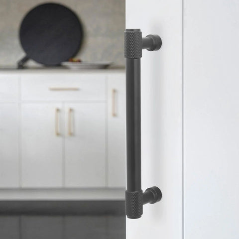 Installed 5-inch matte black knurled cabinet handle shown on white kitchen cabinet