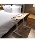 Heavy Duty Rolling Laptop Desk With Secure Locking Brake Casters Adjustable Mobile Workstation Table For Bed Sofa Living Room Home Office Gaming Lounge Setup placed beside a bed.