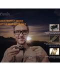 Man holding HM65R Dual Beam Headlamp With USB C Rechargeable 1400 Lumen Output against sunset backdrop, feature highlights shown.