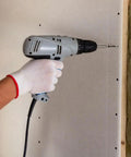 Hand holding a drill fastening Heavy Duty Coarse Thread Drywall Screws With Phosphate Coating to drywall.