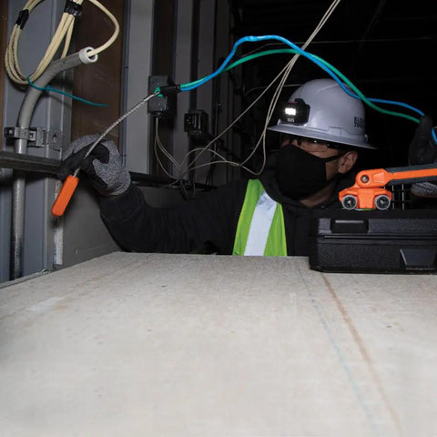 Worker using Pro Grade Magnetic Wire Puller For Behind Walls And Tight Spaces With Rare-Earth Magnets, Stainless Steel Leader, And Rolling Mar-Resistant Wheels