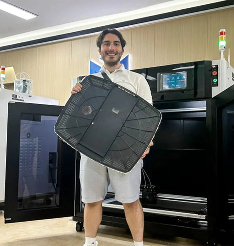 Person holding large 3D printed part in front of MD-1000D Industrial Grade 3D Printer With Fully Enclosed Cabinet, 1000mm build volume.