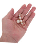 Eight Piece Pearl Waist Tightener Pin Set Elegant Alloy Dress Cincher Clips held in hand for loose trousers and gap filling.