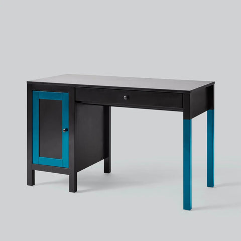 Black desk with blue accents, featuring a cabinet and drawer, minimalist design on a light grey background.