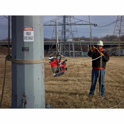 Portable Lineman Magnetic Drill Kit suspended beside a worker, used for heavy-duty metal cutting on job site.