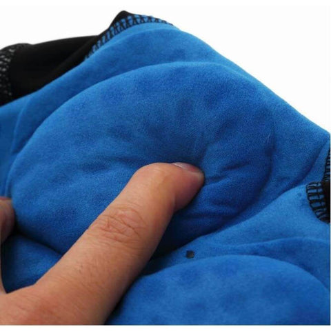 Close-up of finger pressing into the blue padded surface of a cushion, highlighting the soft texture and detailed stitching.