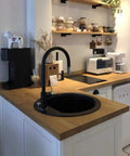 Modern kitchen with wooden countertop, black faucet, appliances, and shelves with jars. Showcases kitchen decor and organization.