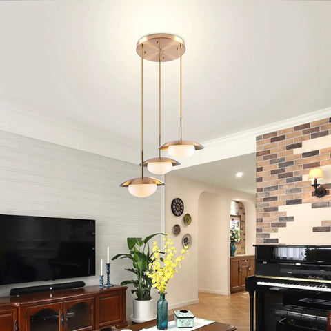 Go-To Three-Light Modern Pendant Lighting With Double Shades And White Glass Globe Inside Brushed Brass UFO Fixture installed in living room