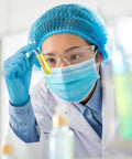 Anti-fog lens wipes front view; scientist in blue PPE with mask and goggles holds a yellow liquid test tube.