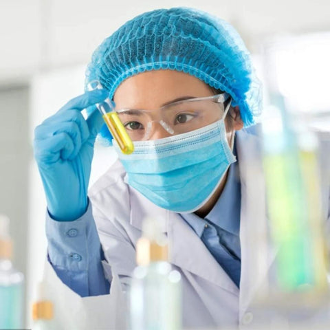 Anti-fog lens wipes front view; scientist in blue PPE with mask and goggles holds a yellow liquid test tube.