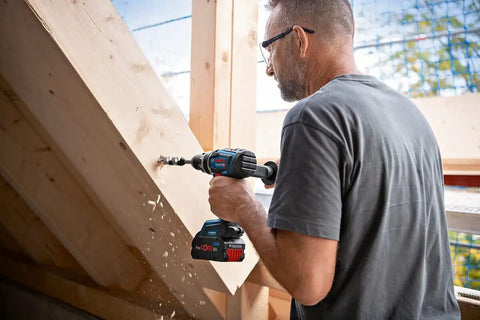 User operating an 18V Cordless Combi Drill with 150 Nm Torque Brushless Motor Pro Grade Power Tool on wooden beams.