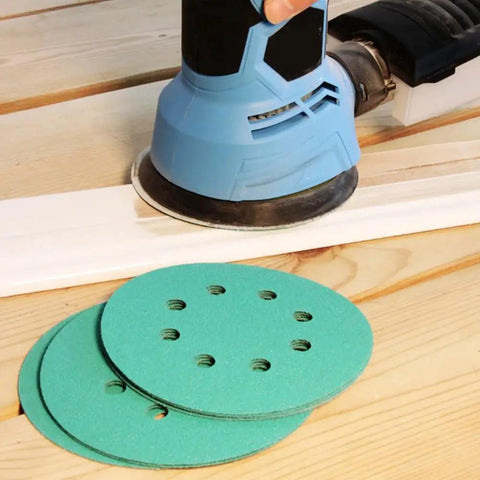 Get 100 Piece Of 5" Sanding Discs With Hook & Loop Back For Wet And Dry Work Featuring 16 Grits From 40 To 1500 Using Premium Silicon Carbide And Zirconium For Heavy Duty Smoothing Jobs That Will Not Clog Or Wear Out Too Fast. Close-up of sanding discs in use.