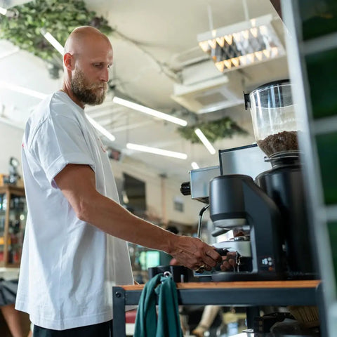 Electric Auto Leveling Espresso Tamper for 57.3 Mm Portafilters in use at a coffee shop by a barista.