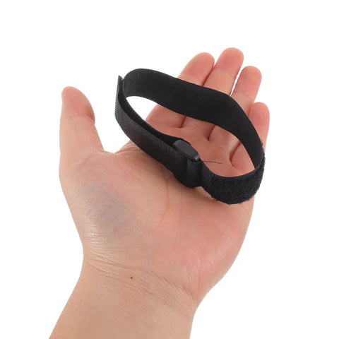 Hand holding one black strap from Sectional Couch Connector Straps 30 Pack With Hook And Loop Fasteners To Keep Modular Sofas Stable For Home And Office Use Quick Connect Reusable Fastening For Easy Sofa Section Alignment.