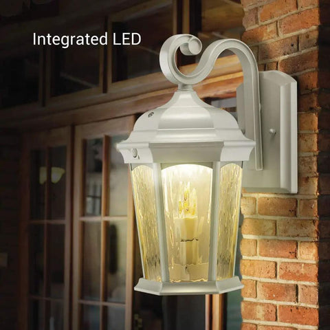 Lit Flickering Flame Lantern With Frosted Glass And Integrated Security Light 3000K Warm Glow Photocell And Motion Sensor Dusk To Dawn Outdoor Wall Lantern With Oil Rubbed Bronze Housing mounted on brick wall.