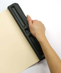 Hand using Adjustable Three Hole Punch For Office Documents With 11 Sheet Capacity Black Metal Punch Tool on paper