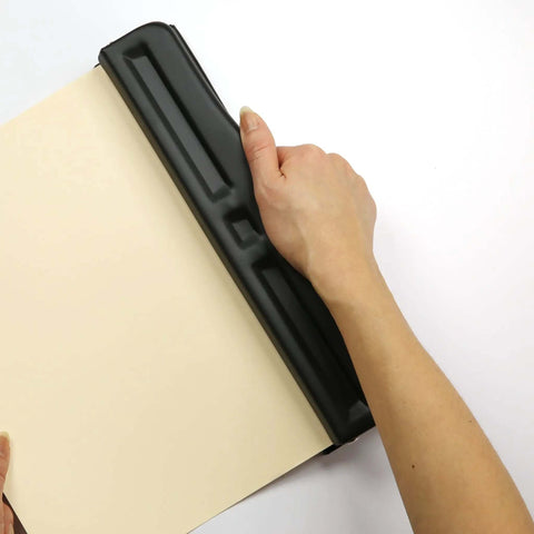 Hand using Adjustable Three Hole Punch For Office Documents With 11 Sheet Capacity Black Metal Punch Tool on paper