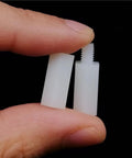 Four Box White Nylon Insulated M2.5 M3 M4 Hex Standoff Spacers Set With Screws Nuts Washers 850 Pcs Value Pack For Electronics And DIY Projects Easy To Use, white hex spacer held by fingers