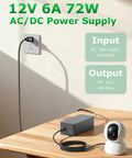 12V 6A Power Supply Adapter 72W With A Go-To 10ft Cord connected to a power outlet, next to a CCTV camera on a table