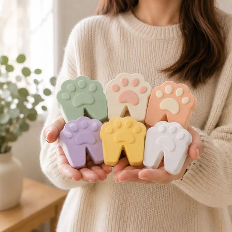 Person holding Six Pack Soft Foam Paw Shaped Door Stoppers For Finger Pinch Protection In Pastel Colors Sage Cream Peach