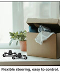 Four Pack Heavy Duty Furniture Mover Dolly Set With Three Wheel Design Built From Carbon Steel And ABS For Moving Heavy Cabinets, Appliances, And Furniture In Homes, Offices, And Warehouses., two black dollies beside a moving box on a windowsill