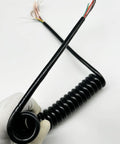 Slick Black Braided Expandable Power Cord With Coiled Spring Design offers auto-retracting action, showcased in a hand.