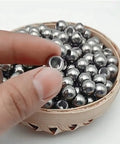 Close-up of stainless steel M6 threaded ball with drilled hole; silver spheres in a wooden bowl (set).