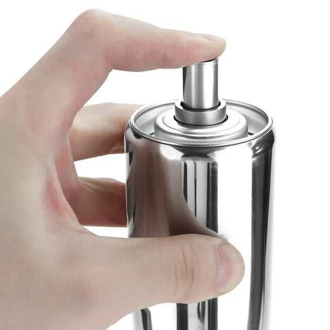 Person pressing top of a stainless steel spray canister, close-up view