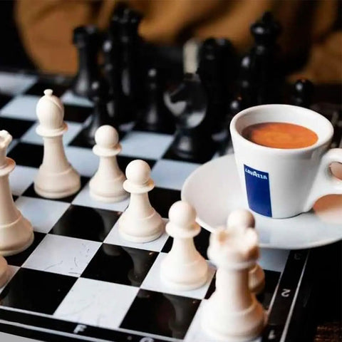 Chess board with white and black pieces, Lavazza espresso cup on the side