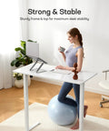 Person sitting on exercise ball at Glass Standing Desk With Drawer 37 X 22 Inches Adjustable Height With Four Preset Levels One Piece Tempered Glass Top White Ergonomic Home Office Desk For Standing Work.