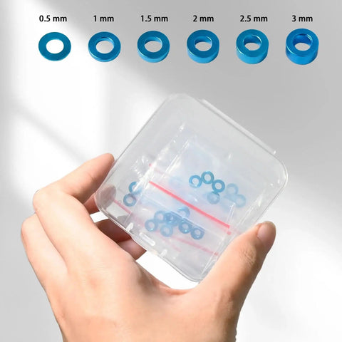 Hand holding 24 Piece M3 Aluminum Shock Tower Mount Washer Kit, shown in transparent box, for Tamiya TT-01 TT-02 XV-01 XV-02 RC cars.