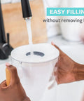 Hands filling 10 Cup Water Filter Pitcher With Bamboo Handle and Coconut Shell Activated Carbon Filter under a faucet