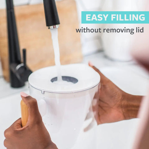 Hands filling 10 Cup Water Filter Pitcher With Bamboo Handle and Coconut Shell Activated Carbon Filter under a faucet