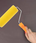 Textured Sponge Paint Roller For Wall Painting With Ergonomic Handle held in hand, showcasing yellow sponge material and ergonomic design.
