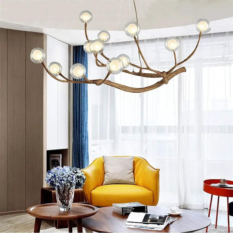 Modern Glass Bubble Chandelier With Sleek Wood Branch Accents, Rustic Industrial Flush Mount Pendant Light For Living Room, Adjustable Hanging Lamp serving over a yellow armchair.