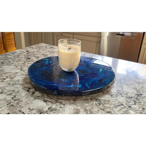 Ocean Resin And Wood Fifteen Inch Lazy Susan With Handcrafted Wave Pattern For Kitchens And Dining Tables Smooth 360 Degree Rotation Serving Tray And Charcuterie Board A Unique Centerpiece And Gift Idea with a glass of milk on top on a marble countertop.