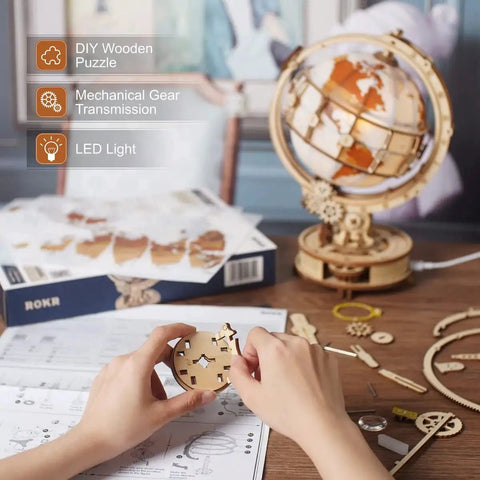 LED Illuminated 3D Wooden Globe Puzzle For Adults With Stand Build Your Own Night Light World Globe Kit 180 Pre-Cut Pieces Educational Decor Gift For Birthday Or Anniversary, hands assembling wooden globe parts on desk