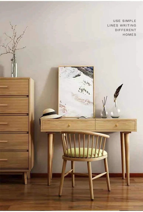 Minimalist wooden desk setup with chair in a cozy room, next to a tall chest, featuring natural decor accents and a framed artwork.